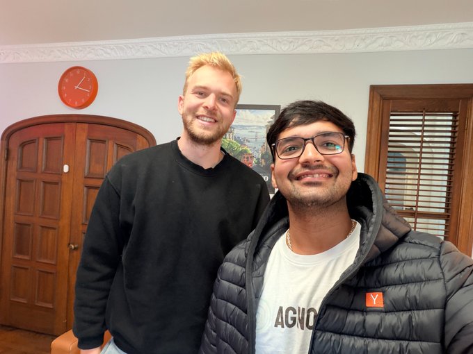 Two smiling men pose indoors, with the person in front wearing a puffer jacket featuring a small red “Y” patch and a shirt reading “AGNO.” The caption says they met “@gregpr07,” the “OG browser use man,” and closes with “wagmi.”