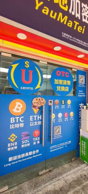 The exterior of a cryptocurrency exchange shop with blue signage displaying 'U CRYPTO', 'OTC', and various coin logos including BTC, ETH, BNB, SOL, and TRX, with Chinese text and the shop name 'YauMaTei'.