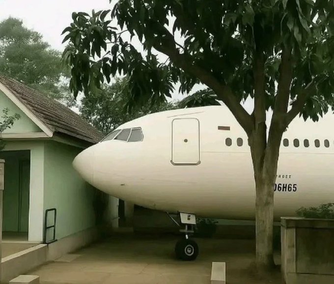 An old commercial airplane, with registration "06H65," appears to have crashed into the side of a green house, with its nose protruding through the wall beneath a large tree.

The image humorously illustrates the poster's crypto-fueled aspirations of one-day owning a private jet, with the awkwardly positioned plane serving as a visual punchline to their dream of wealth through $STKR.