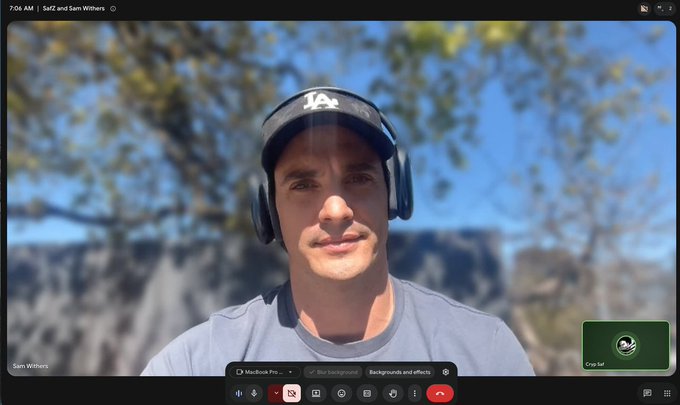 A Google Meet video call screenshot showing a man named Sam Withers wearing a black LA cap and headphones, outdoors with a blurred background, at 7:04 AM on Sat 2nd.