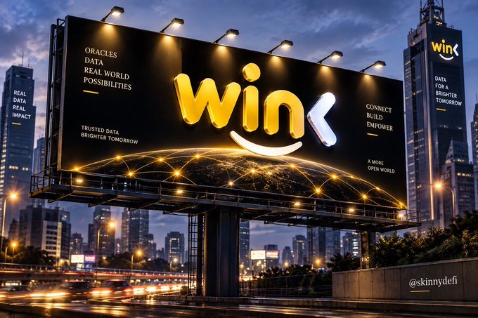 A large illuminated billboard displays the yellow 'wink' logo with the surrounding text 'ORACLES DATA REAL WORLD POSSIBILITIES', 'CONNECT BUILD EMPOWER', and 'A MORE OPEN WORLD' against a nighttime city backdrop.