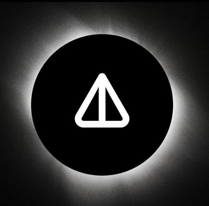 A black circular graphic with a white glowing halo surrounding it, containing a white triangular play button or logo in the center.