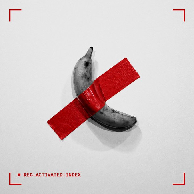 Black and white banana taped with red duct tape on a white background, framed by camera viewfinder marks with the text "REC-ACTIVATED: INDEX."