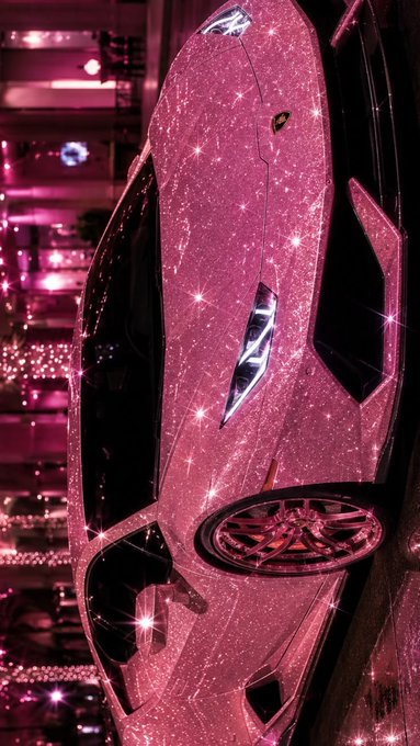 A pink sparkly crystal-encrusted Lamborghini covered in rhinestones, displayed against a pink-lit background.