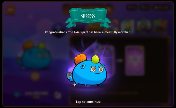 A "SUCCESS" notification screen from the game Axie Infinity displays a congratulations message: "Congratulations! The Axie's part has been successfully morphed," featuring a cute blue Axie character with orange hair and clock eyes surrounded by a purple glow, with "Tap to continue" prompting at the bottom. This directly illustrates the post's mention of the "Meta Morph" feature in Origins, which allows players to swap cards using parts from other Axies they own.