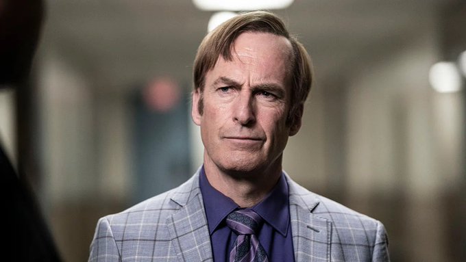 The image features a man wearing a suit, tie, and blue plaid shirt with his head tilted slightly to one side as he looks off into the distance. The background of the image shows an empty hallway or corridor, which could be part of a movie set or a real-life setting. The caption "Better buy $ZEC" suggests that there is a sale going on for this particular suit and tie in the market.
