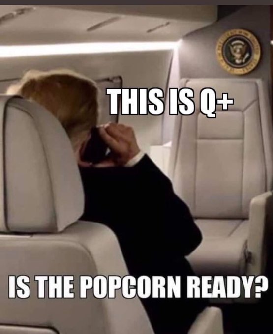 A meme featuring Donald Trump on Air Force One covering his face, with text reading 'THIS IS Q+' and 'IS THE POPCORN READY?'.
