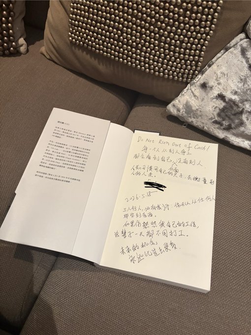 The image features a book open on a couch cushion with Chinese writing on it. The text appears to be in a foreign language or script that is not easily recognizable. The book's cover has a design of beads, adding an artistic touch to its appearance. The scene suggests that someone has been jotting down their thoughts and ideas about the book they are reading, possibly in a foreign language.
