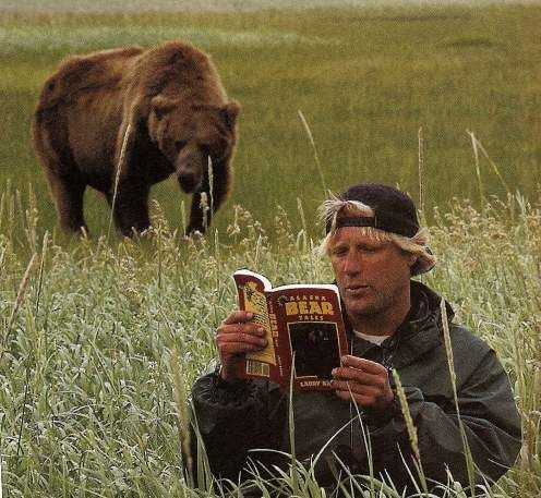 A man wearing a backwards cap calmly reads a book titled "BEAR ATTACK" in a grassy field while a large brown bear approaches from behind, illustrating the post's warning about the precarious state of L2 crypto narratives and the "Blast" shutdown announcement amid unsustainable network costs.