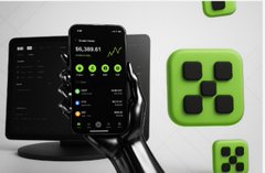 The image features a hand holding up a smartphone displaying an app called Bitcoin Cash, which has green squares with numbers scattered across its screen. The hand holds the phone at a slight angle towards the bottom of the frame. In the background on the right side, there is another square filled with green numbers but positioned higher than the hand's display and slightly to the left.