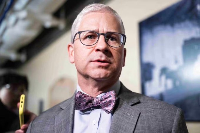 Former Congressman Patrick McHenry, wearing a purple paisley bow tie and glasses, speaks to reporters, with the image accompanying news of his warning about the upcoming CLARITY Act vote on September 15 and its potential impact on the midterm elections.