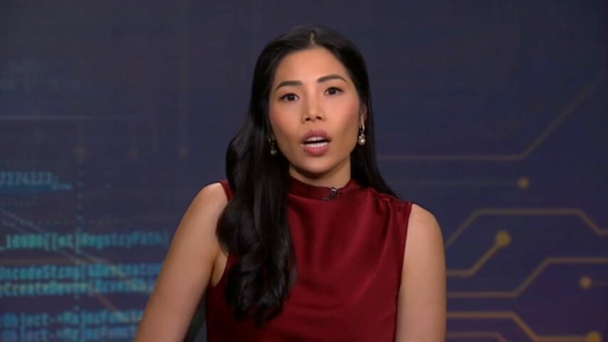 The image shows a woman wearing a red top with her mouth open, possibly speaking or making a facial expression. The background features a blue computer screen displaying lines of code, which could be related to the topic of Bitcoin whale buying by SpaceX. The caption below the image reads "Is SpaceX quietly becoming a Bitcoin whale? SpaceX bought 18,712 BTC and is treating them as a Treasury reserve asset on the same level as cash or bonds".
