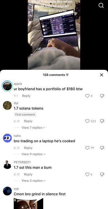 A TikTok screenshot titled "What it sounds like when ur bf tries to explain axiom and crypto" shows a person on a bed using a laptop displaying crypto trading screens, with a hand pointing at the screen, while 128 comments below feature users mocking small crypto portfolios including "ur boyfriend has a portfolio of $180 btw," "1.7 solana tokens" (223 likes), "bro trading on a laptop he's cooked," "1.7 sol this man a bum," and "Cmon bro grind in silence first," reflecting the poster's complaint about beginners receiving hateful comments for starting with small holdings like single Solana tokens.