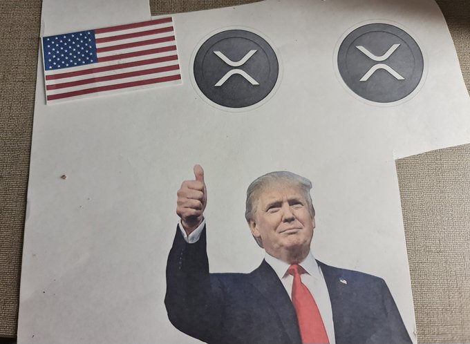 This image features a print of U.S. President Donald Trump giving a thumbs-up, accompanied by two XRP cryptocurrency logos and an American flag.