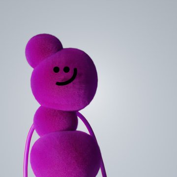 The image features a purple, fluffy stuffed animal with a big smiley face drawn on its head. The animal appears to be posed for a photo or video, possibly as part of an advertisement or promotional material. The background is a plain white wall, which contrasts with the vibrant colors and playful nature of the plush toy.