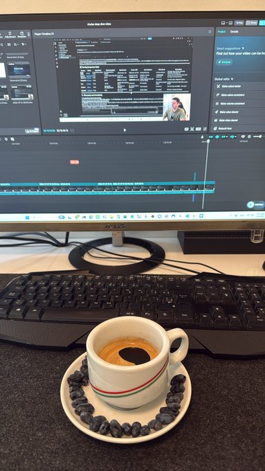 A workspace setup showing a computer monitor displaying video editing software, with an espresso cup and saucer made of coffee beans placed on the desk.