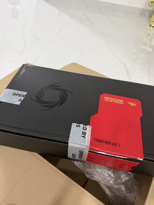 A black shipping box with an MSI dragon logo and custom red tape reading 'RIOTBOUND COLLECTIBLES' and 'TOGETHER AS 1', partially opened inside a cardboard shipping container.