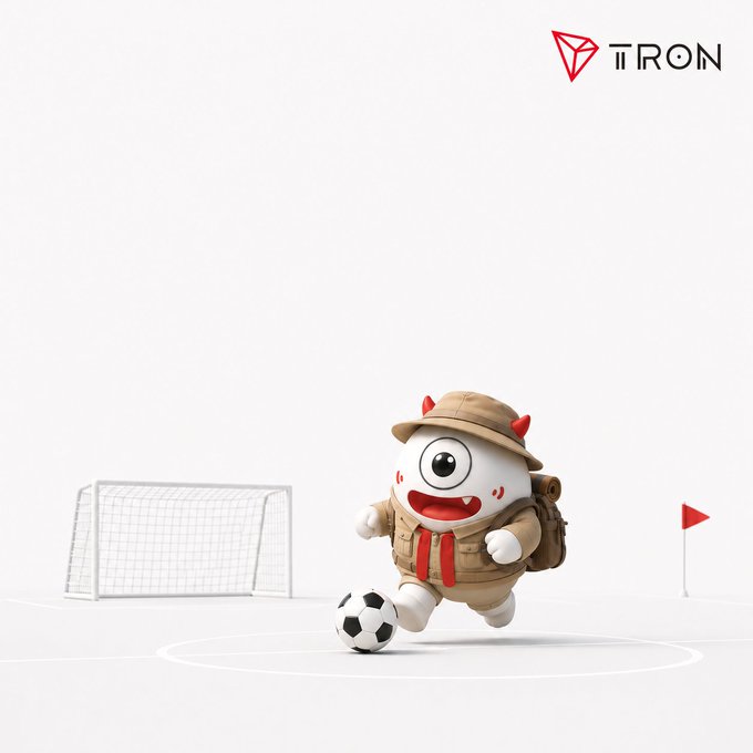 A cute one-eyed cartoon mascot dressed as a safari explorer kicks a soccer ball toward a goal on a white field, with the "TRON" logo displayed in the top right corner. The image mirrors the post's football analogy, visually representing TRON blockchain as the "playmaker" circulating transactions across the network.