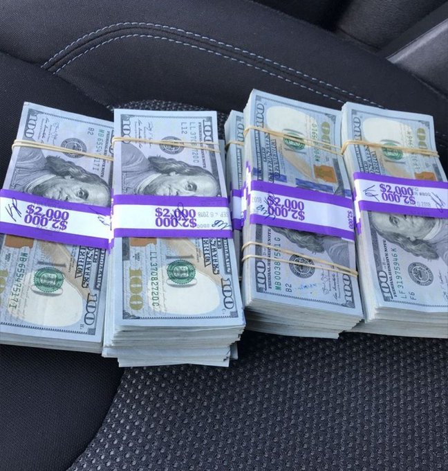 Four stacks of US $100 bills, each banded with purple straps labeled "$2,000," rest on a black leather car seat, visually embodying the post's message by displaying bundled cash as a symbol of financial growth and accumulating wealth.