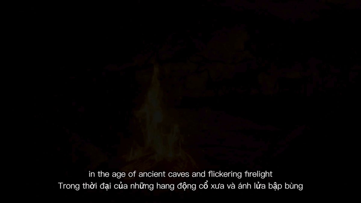 The image features a black background with white text that reads "In the age of ancient caves and dicker firelight. Thong their idia háng di và có cái tin này mới chú bò TRON Bull quen thuộc đã chính thức lộ diện với mạo hoàn toàn mới, nhìn chiến và hiện đây". The image is accompanied by a fire in the background.