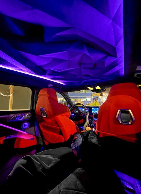 The image shows a car interior with purple lighting that creates an interesting visual effect. The perspective of the photo suggests that someone is sitting inside the car, possibly taking a picture or recording a video. The image also contains text related to Algorithms, specifically about Bitcoin and Ethereum wallets. This information might be useful for those interested in cryptocurrency or digital finance.