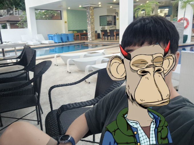 Person relaxing at a poolside resort with an animated Bored Ape-style monkey character filter overlaying their face.