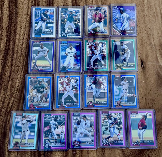 A collection of shiny Topps Chrome baseball trading cards is laid out on a wooden surface, featuring notable players like Kyle Schwarber, Jeremiah Jackson, Tanner Holl, George Valera, Sal Frelick, Brady Tygart, Christian Moore, Hassan Bush, James Tibbs III, Christian Moore, Chase DeLauter, Zeng Fanfan, Logan Webb, Andy Rodriguez, Max Prince, Drew Vlais, and Boston Wallner, all displayed in protective sleeves. The image showcases the colorful "hitties" (hits) the user pulled from their full Topps Chrome hobby case, highlighting the variety of parallel and rookie cards they collected.