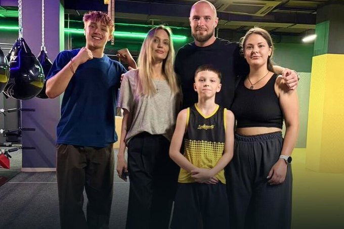The image shows a woman resembling Angelina Jolie, along with four others, posing together in what appears to be a boxing gym, with a young boy in the center wearing a yellow and black athletic jersey. The accompanying post suggests this is Jolie during her visit to Kharkiv, Ukraine, where she is shown in a setting that contrasts with the criticism directed at Trump administration officials who allegedly avoided such frontline areas.