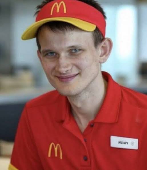 The image shows a young male McDonald's employee wearing the iconic red and yellow visor and uniform, smiling at the camera with a name tag visible. The post humorously uses the image to suggest the commenter is far from reaching their $50K crypto profit goal, as they're $75K away—perhaps implying they need a fast-food job to make ends meet while their crypto investments underperform.
