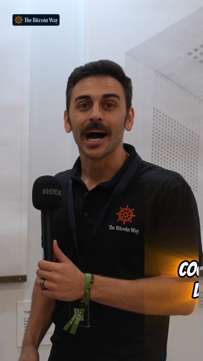 The image features a man wearing a black shirt with an orange logo and holding a microphone. The background of the image shows a white wall with a poster hanging on it that says "The Bitcoin Way". This suggests that the man might be discussing or promoting the concept of Bitcoin, which is a digital currency. The post also mentions that Bitcoin empowers individuals to pursue their dreams by providing them with self-custody and freedom from traditional financial systems.