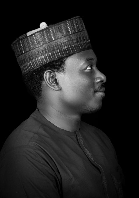A black-and-white profile portrait of a man wearing a traditional patterned cap (fula) and dark embroidered attire, gazing upward against a black background, paired with a "Good morning, Arewa" greeting wishing followers a "making $SUNUSI day."