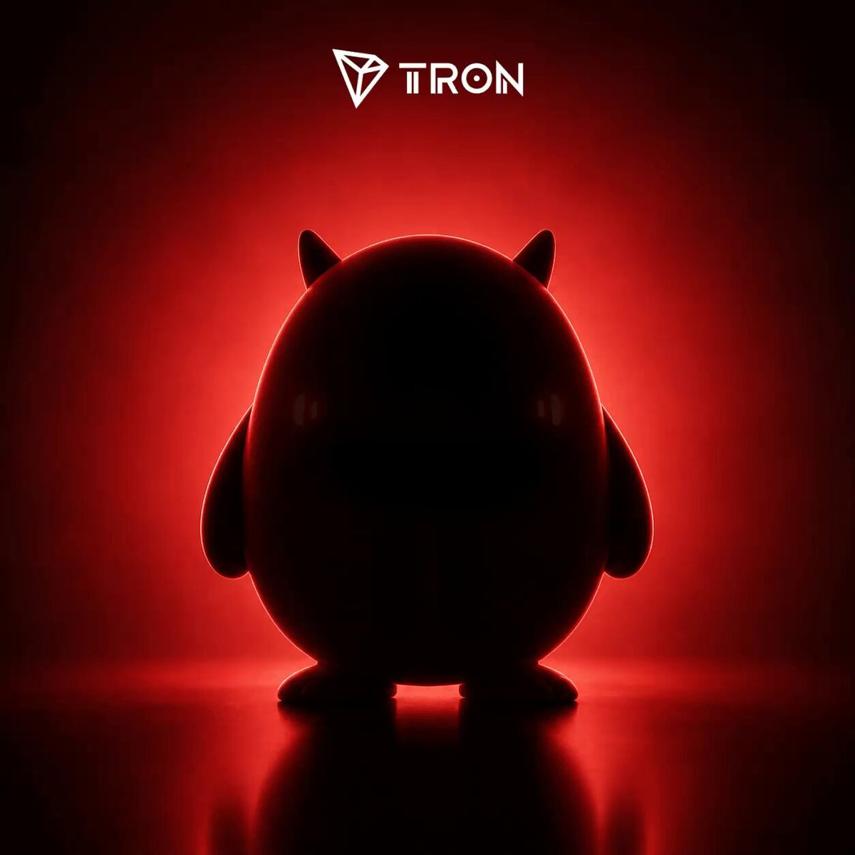 The image features a toy figure of a cute, round animal sitting against a red background. The toy appears to be a small, furry creature with rosy cheeks, giving it an endearing appearance. The toy's position and the red background create a striking contrast that makes it stand out prominently in the image.