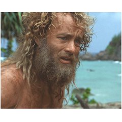 A close-up portrait of a man with long, curly, sun-bleached hair and a thick beard, looking disheveled with a beach and ocean visible in the background.