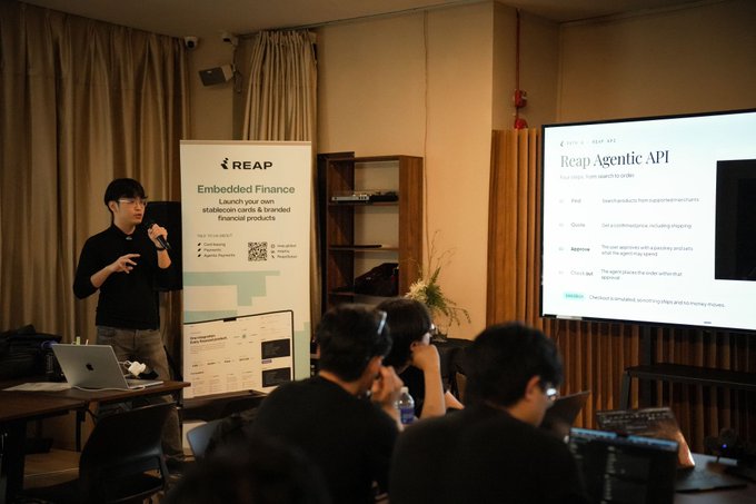 A presenter speaks at a Reap event, standing next to a 'Reap Agentic API' projection and a banner advertising 'Embedded Finance' services.