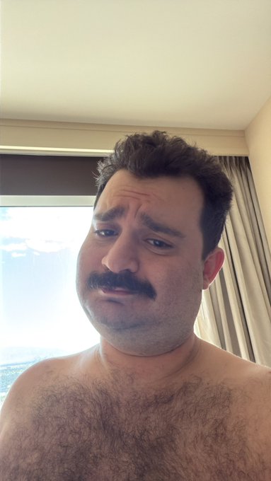 A shirtless man with a mustache makes a skeptical, unimpressed facial expression in what appears to be a hotel room. His doubtful look perfectly mirrors the post's message mocking those still waiting for a major market move, only to be met with sideways consolidation instead.