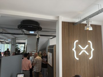 The image shows a group of people gathered around a table at an event called "XRP Ledger research summit" in Paris. The attendees are engaged in discussions about XRP Ledger solutions, such as off-chain smart contracts and consensus mechanisms. There is also a poster on the wall that reads "Focus on what is in the image and how it relates to the post". The people present appear to be passionate about their work and eager to learn more about the emerging technology of interest.