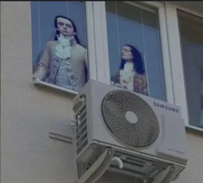 Two men in 18th-century colonial attire stand behind a window where a Samsung air conditioning unit has been mounted on the exterior, awkwardly obscuring the lower portion of the window frame.