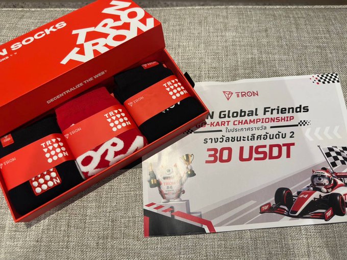 A TRON Socks branded box containing socks, next to a promotional card for 'TRON Global Friends GO-KART CHAMPIONSHIP' offering 30 USDT.