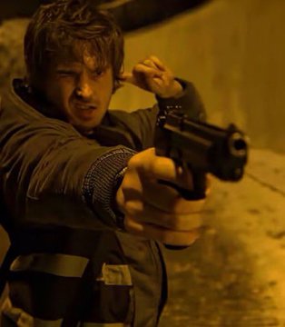 A young man with brown hair aims a pistol forward with one hand while plugging his ear with the other, bathed in warm yellow light.