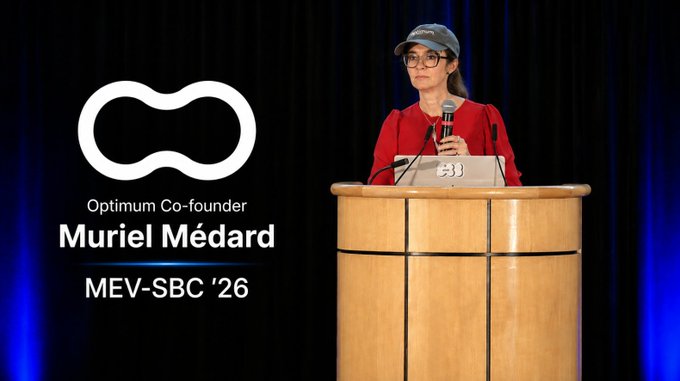 A presentation slide showing Muriel Médard, Co-founder of Optimum, speaking at a wooden podium at MEV-SBC '26, with the Optimum infinity-style logo displayed beside her.