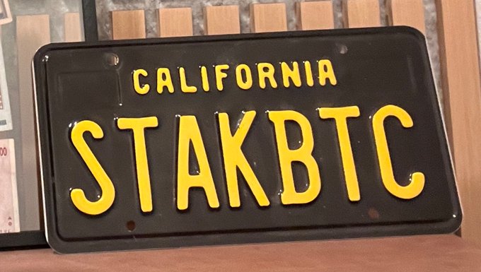 A black California-style license plate with yellow text reading "CALIFORNIA STAKBTC", likely a misspelling of "STANKBTC".