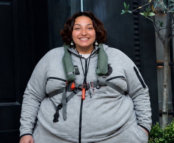 A smiling woman in a gray Patagonia fleece and green life vest harness stands outside, with the caption "no world cup match today — at least donors can use their money to eat today — a downtrend day for Polymarket" humorously contrasting the upbeat, well-fed subject with the bearish market sentiment and trading lull.