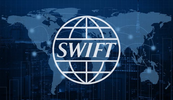 The image features a logo with the word "SWIFT" written in white letters against a blue background, which represents the SWIFT organization. The text below the logo reads "BOOOOOOOOOOM SWIFT confirms crypto rails are coming to global banking. Over 50 major banks, including Bank of America, JP Morgan, Deutsche Bank, Bank of China, and SBI, are backing the initiative for cross-border payments. $XRP". This image is related to a post that discusses the use of cryptocurrency in the financial industry, specifically highlighting the SWIFT organization's involvement in this emerging technology.