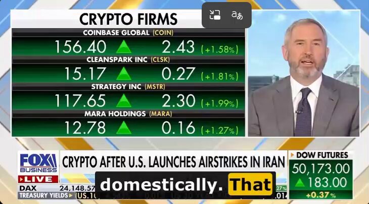 The image shows a man wearing a suit talking about cryptocurrency markets on a TV screen. The text on the screen reads "Crypto Firms", which indicates that they are discussing crypto-related topics. The man's face can be seen, but his expression is not clear enough for us to determine if he is happy or sad.