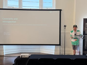 A presenter standing at a podium giving a presentation titled 'Covenants and introspection' with a subtitle referencing 'Quantstamp', displayed on a projection screen.
