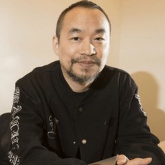A man with a short beard and mustache, wearing a black button-up shirt, smiles at the camera.