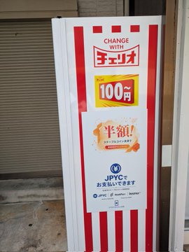 A red-and-white striped vending machine accepts JPYC (Japanese Yen Coin) cryptocurrency payments, with promotional signage offering a "100 yen" canned beverage special ("CHANGE WITH チェイ coin") and advertising half-price ("半額!") deals on JPYC-supported drinks. The image supports the post's excitement about discovering a vending machine that accepts JPYC digital currency for affordable soda purchases.