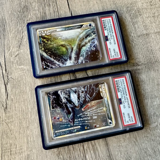 Two graded Pokémon cards featuring Lugia in PSA slabs displayed on a wooden surface, with labels indicating '2008 POKEMON JAPANESE', 'GEM MT 10', and 'LUGIA LEGEND HOLO ED'