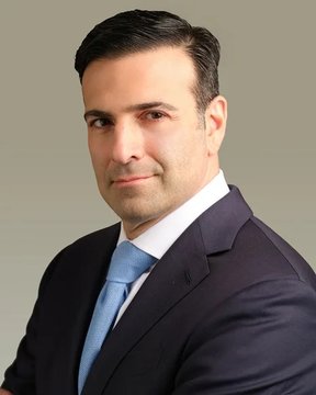 A professional headshot shows a man in a dark navy suit, white dress shirt, and light blue tie, posing against a neutral gray background. The image accompanies a quote from Circle President Heath Tarbert discussing how USDC's low transaction costs will enable AI agent-to-agent commerce.