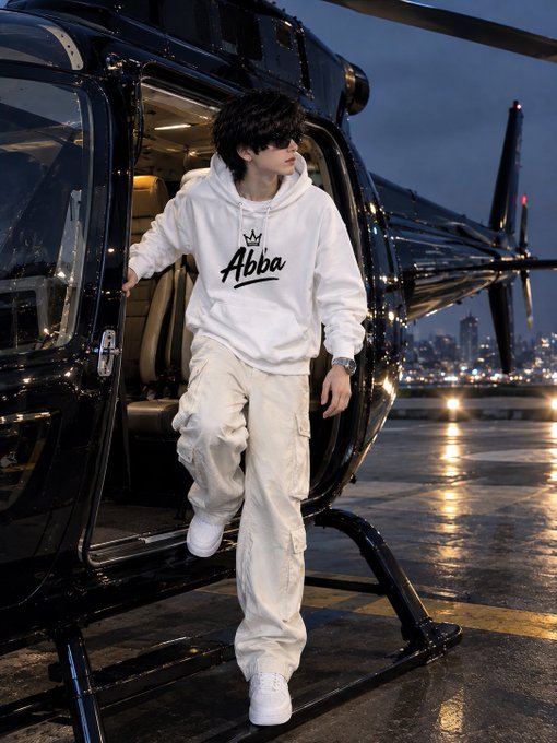 A young person stepping out of a black helicopter at dusk, wearing a white 'Abba' hoodie, beige cargo pants, and white sneakers, with a city skyline visible in the background.